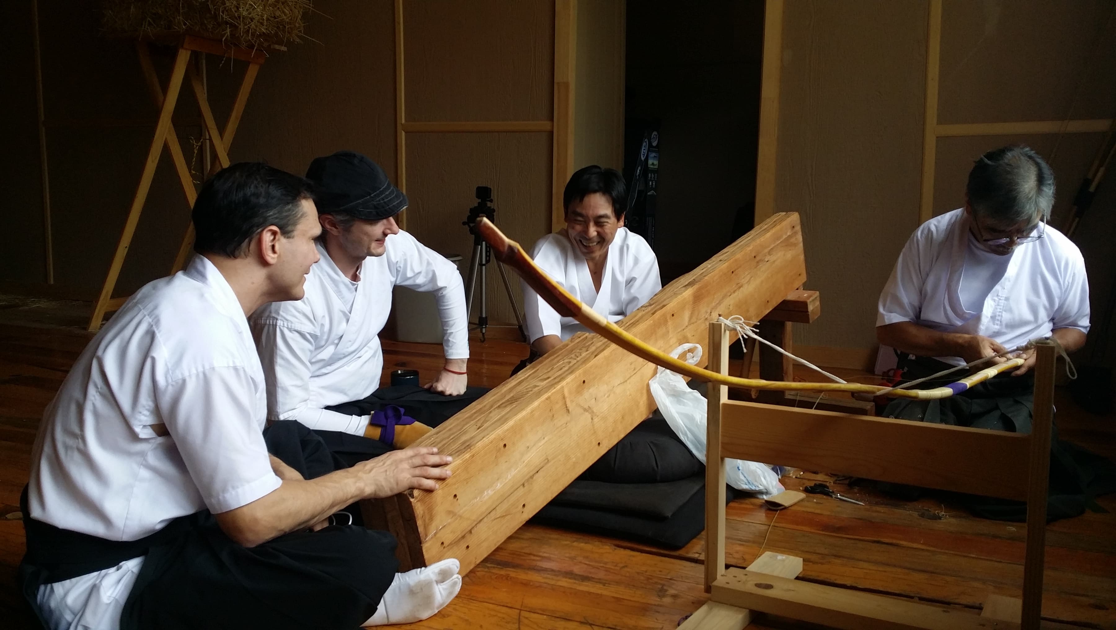 Shibata-sensei repairs a yumi while Jason, John, and Yasuo look on.