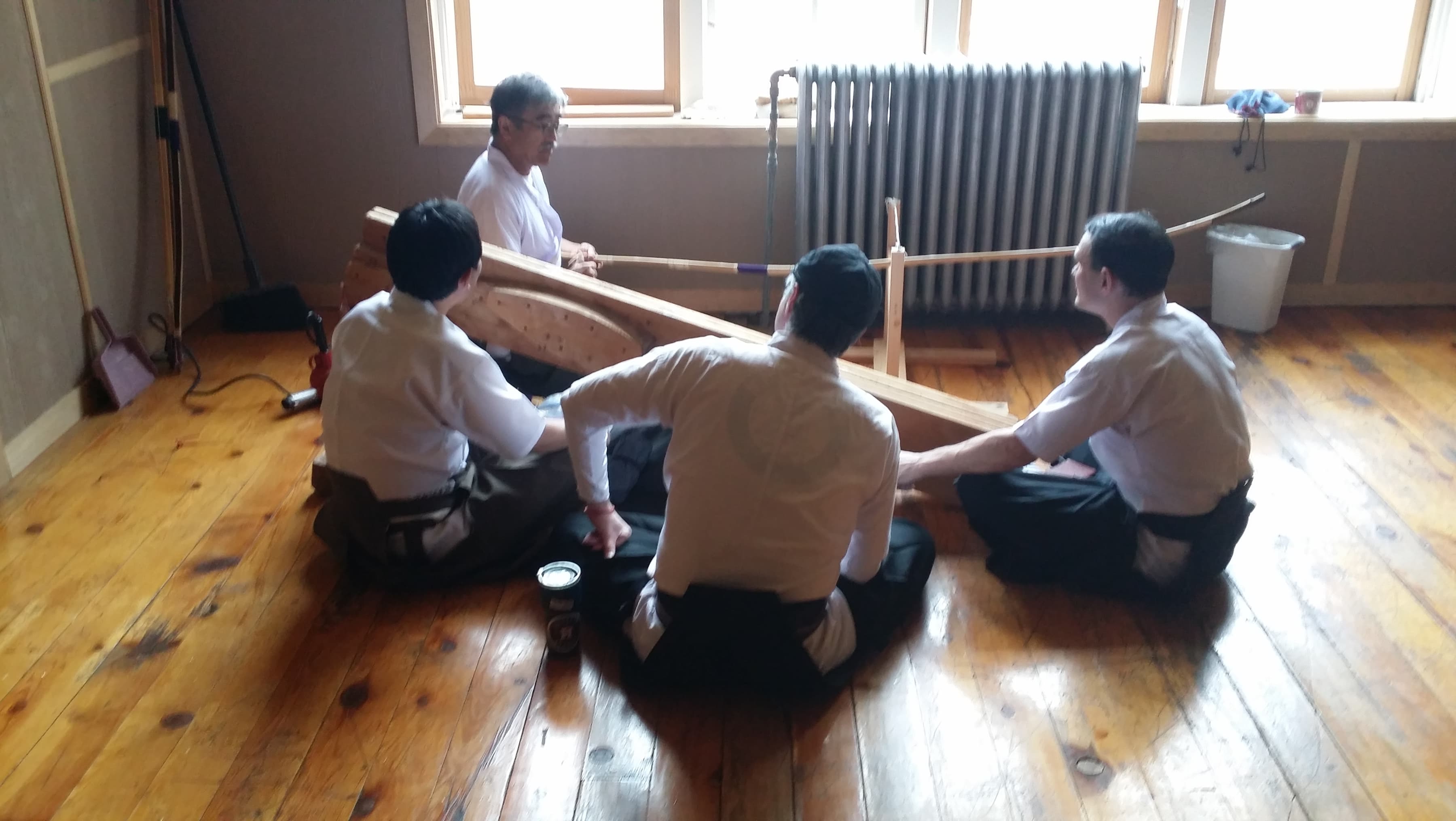 Shibata-sensei repairs a yumi while Jason, John, and Yasuo look on.